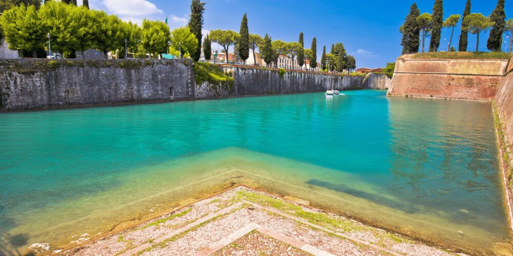 Scorcio di Peschiera del Garda con le mura della città e il canale navigabile con barca nello sfondo