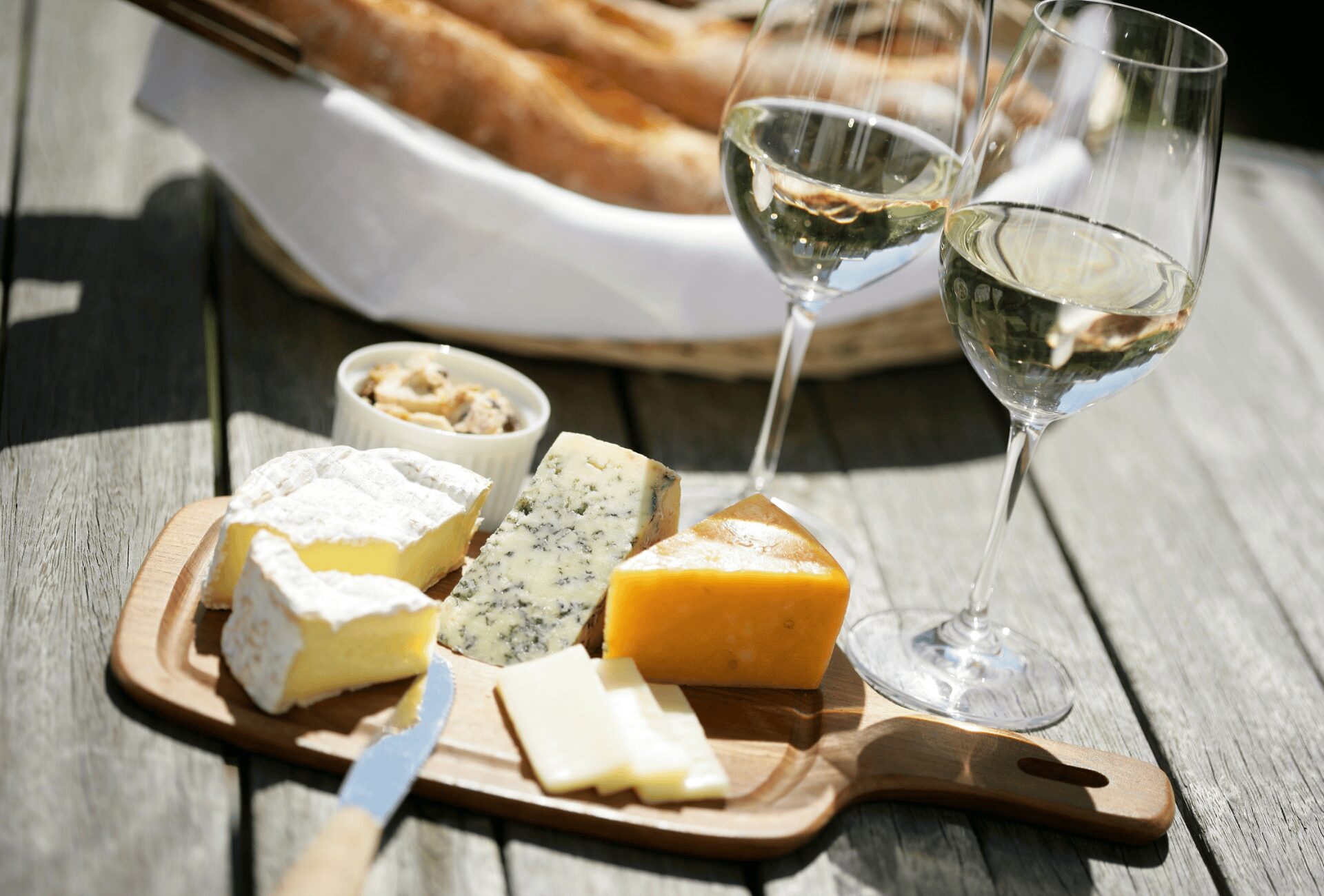 Aperitivo con due bicchieri di prosecco, cesto di pane e tagliere di formaggi